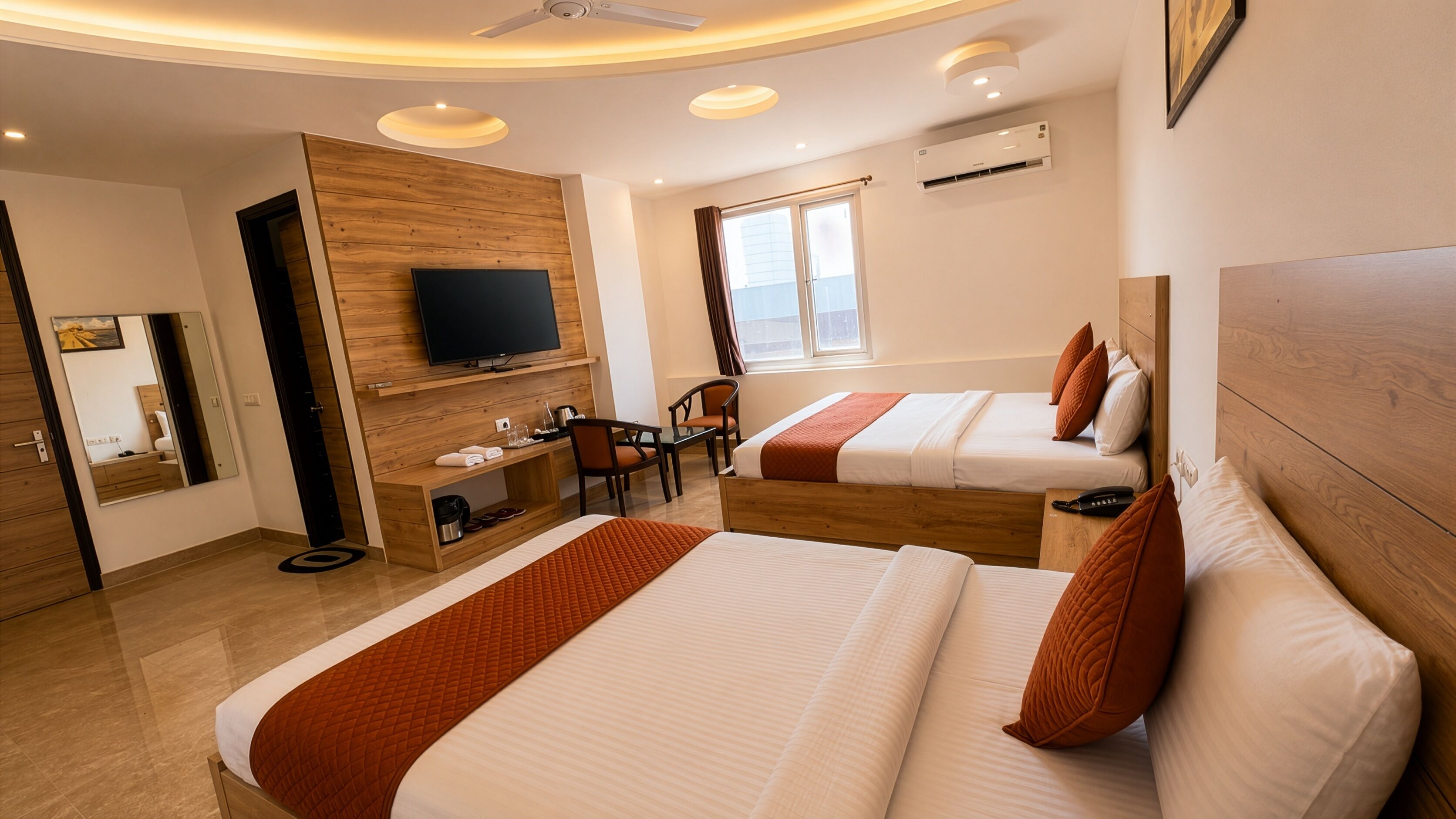 A hotel room with two beds, a TV, a desk, a chair, and a window.