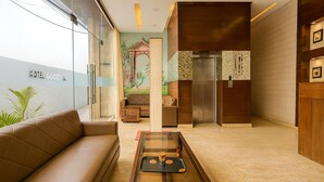 A modern hotel lobby with a leather sofa, a glass coffee table, and a mural on the wall.