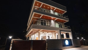 A multi-story modern building with balconies, large windows, and a well-lit entrance. - Silver waves Beach Stay (Udupi)