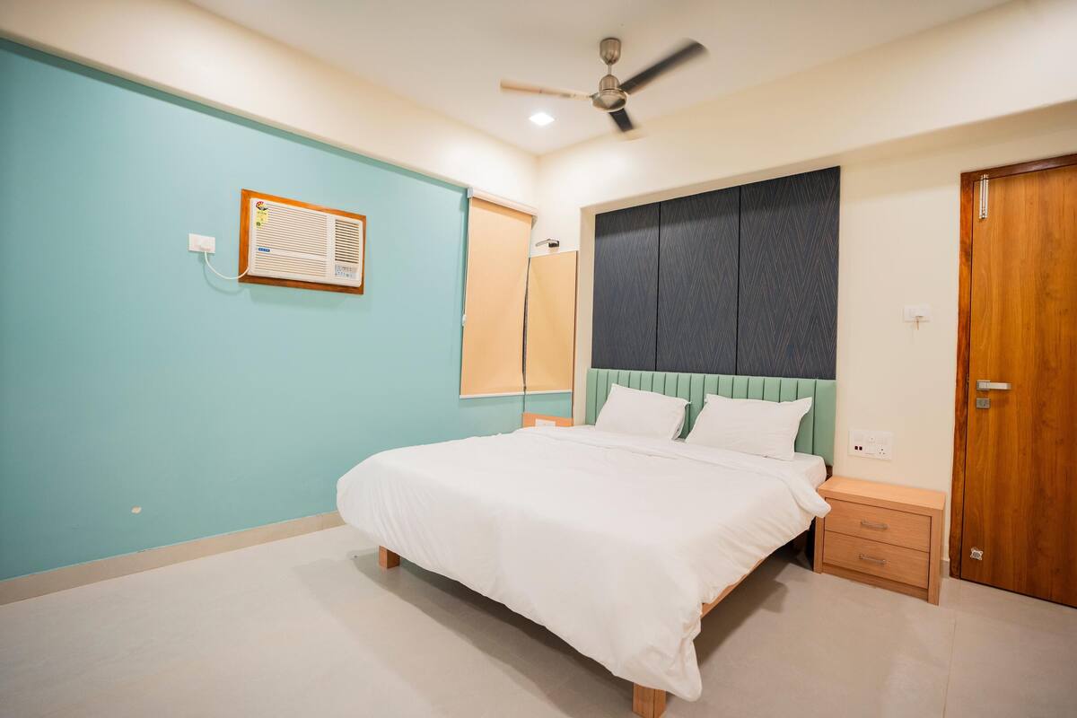 Un dormitorio con cama, mesita de noche, armario, ventilador de techo y aire acondicionado instalado en la pared.