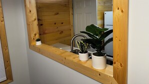 A wooden-framed mirror with a sink and two potted plants.