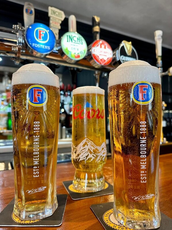 Three tall beer glasses with logos and text on them, placed on coasters at a bar with a tap in the background. - Courtyard Rooms, 1-bed Studio, Sleeps 2, Pets Ok (Northallerton)