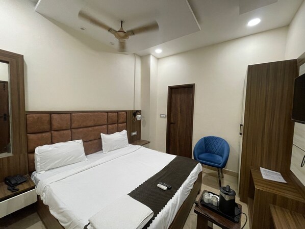 A hotel room with a large bed, a desk, a chair, a wardrobe, and a ceiling fan. - Monga Dreams 120 Mtrs from Golden Temple (Amritsar)