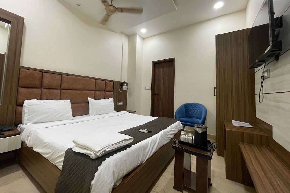 A hotel room with a bed, a chair, a small table, a television, and a ceiling fan.