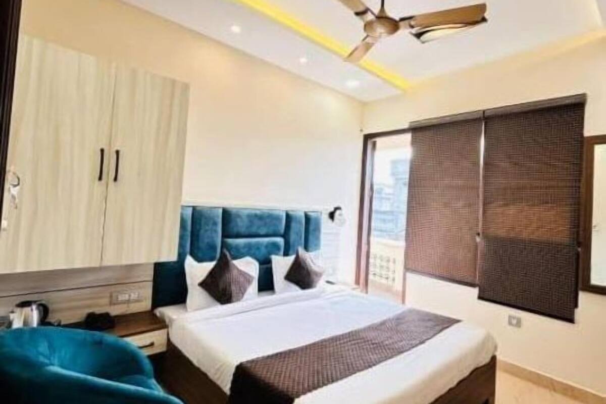 A modern bedroom with a bed, a ceiling fan, a wardrobe, and a view of the city.