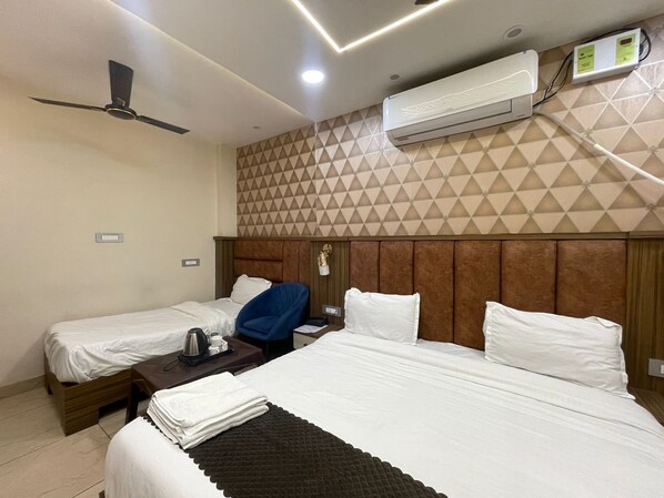 Habitación de hotel con dos camas, un ventilador de techo, un equipo de aire acondicionado y una pared con diseño geométrico.