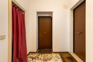 A hallway with a wooden door, a red curtain, and a patterned floor. - Black Sand Studio by Wonderful Italy (Bologna)