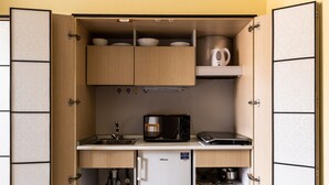 Een praktische keuken met houten kastjes, een magnetron, een koffiezetapparaat en een kleine koelkast.