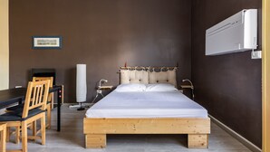 Een slaapkamer met een houten bed, een bureau en een stoel.
