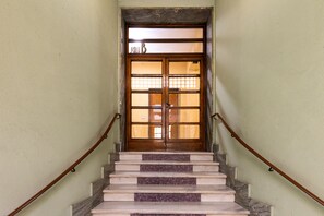 A staircase with marble steps and wooden handrails leading to a wooden door with glass panels. - Black Sand Studio by Wonderful Italy (Bologna)
