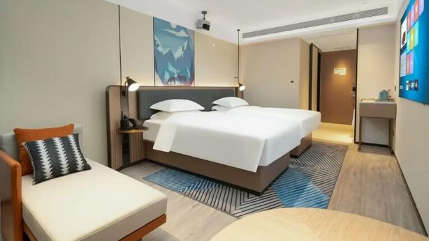 Ein modernes Hotelzimmer mit einem großen Bett, einem Schreibtisch, einem Stuhl und einem Bild an der Wand.