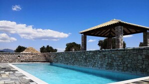 Una piscina con paredes de piedra y una pérgola.