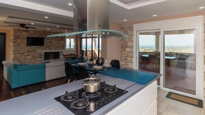Una cocina moderna con una isla central, una pared de piedra y un balcón con vistas.