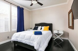 Relax in a spacious room with a large bed, wall-mounted TV, and convenient bedside table.