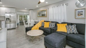 A modern living room with a grey sectional sofa, a round coffee table, and a ceiling fan. - King Bed. Great Parking. Message with Questions.

 (Titusville)