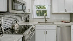 A modern kitchen with white cabinets, a stainless steel kettle, a microwave, and a dishwasher. - King Bed. Great Parking. Message with Questions.

 (Titusville)