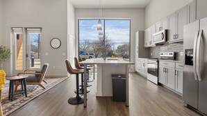 Een moderne keuken met een centraal eiland, roestvrijstalen apparatuur en een groot raam met uitzicht.