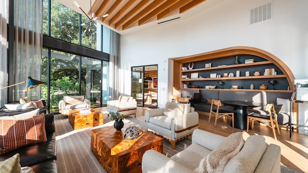 Een ruime woonkamer met een modern design, voorzien van een groot raam, een ingebouwde boekenkast en een gezellige zithoek.