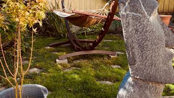 A garden with a hammock, a stone sculpture, and a potted plant.