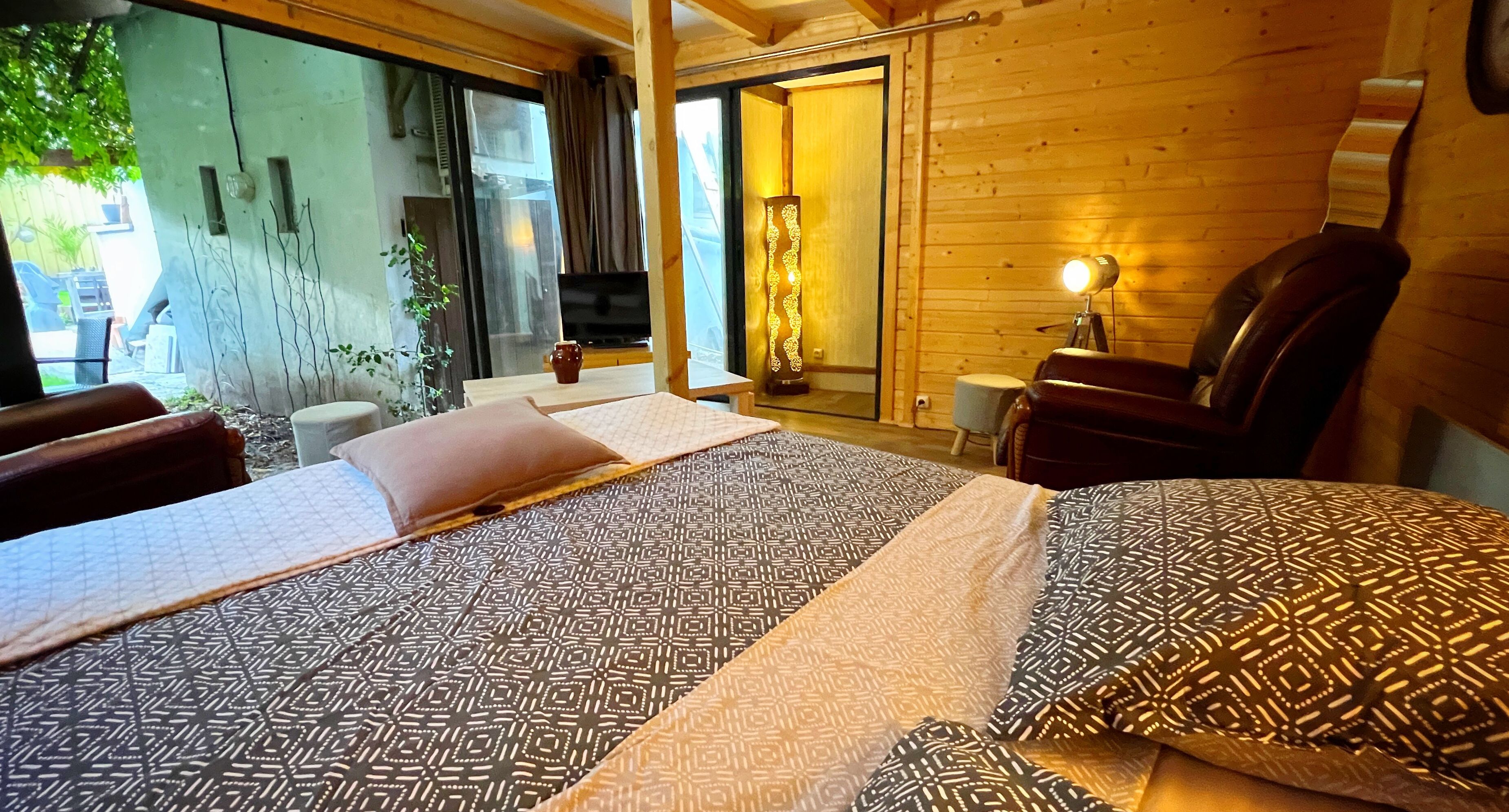 Een slaapkamer met een groot bed, een houten hoofdbord, een televisie, een lamp en uitzicht op het landschap.