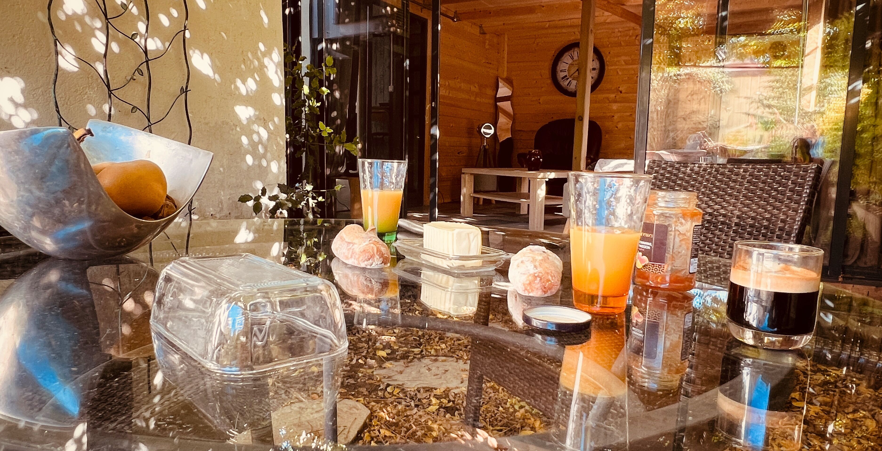 A table with various containers and glasses, likely for beverages, in a room with wooden walls and a clock on the wall.