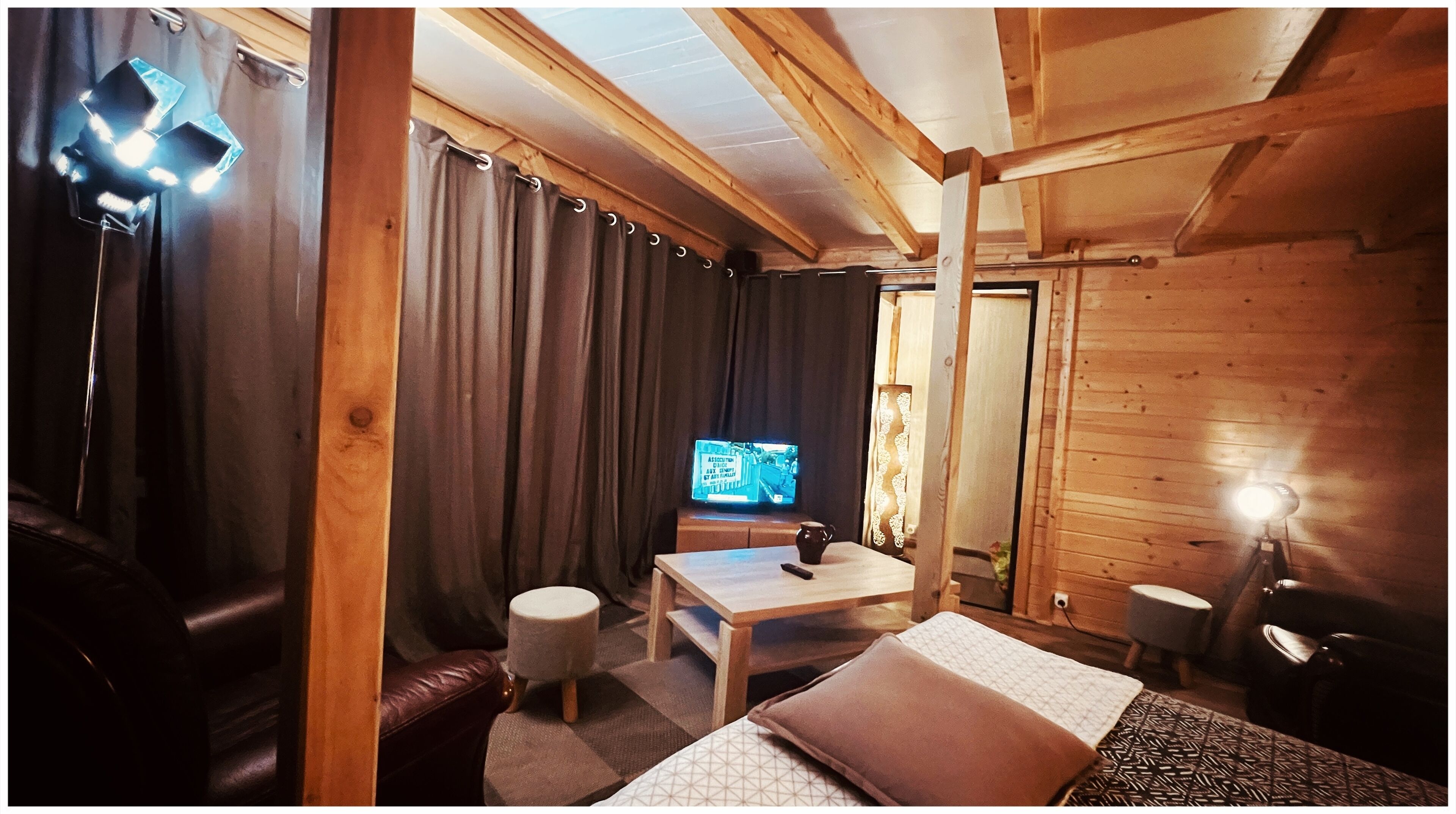 A cozy room with a bed, a small table, a TV, and a lamp.