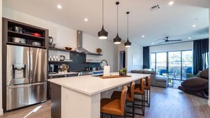 A modern kitchen with a central island, stainless steel appliances, and pendant lighting.