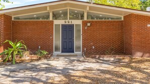 A brick building with a numbered entrance, a covered porch, and a small garden area. - Park Bliss Unit 4. Private Suite
 (Titusville)