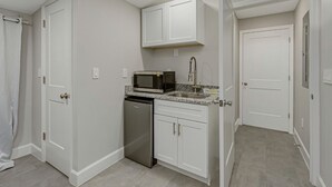 A compact kitchen with white cabinetry, a built-in microwave, and a dishwasher. - Park Bliss Unit 4. Private Suite
 (Titusville)
