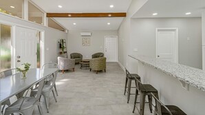 A modern kitchen with a long counter, bar stools, and a dining table. - Park Bliss Unit 4. Private Suite
 (Titusville)
