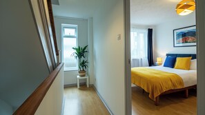 A hotel room with a bed, a potted plant, a window, and a painting on the wall. - Captivating 3-bed House in London (London)