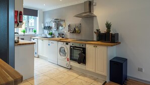 A modern kitchen with a built-in oven, microwave, and dishwasher, wooden countertops, and a window providing natural light. - Captivating 3-bed House in London (London)