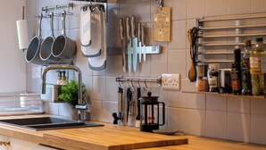 A kitchen with a wooden countertop, stainless steel sink, and various utensils hanging on the wall. - Captivating 3-bed House in London (London)