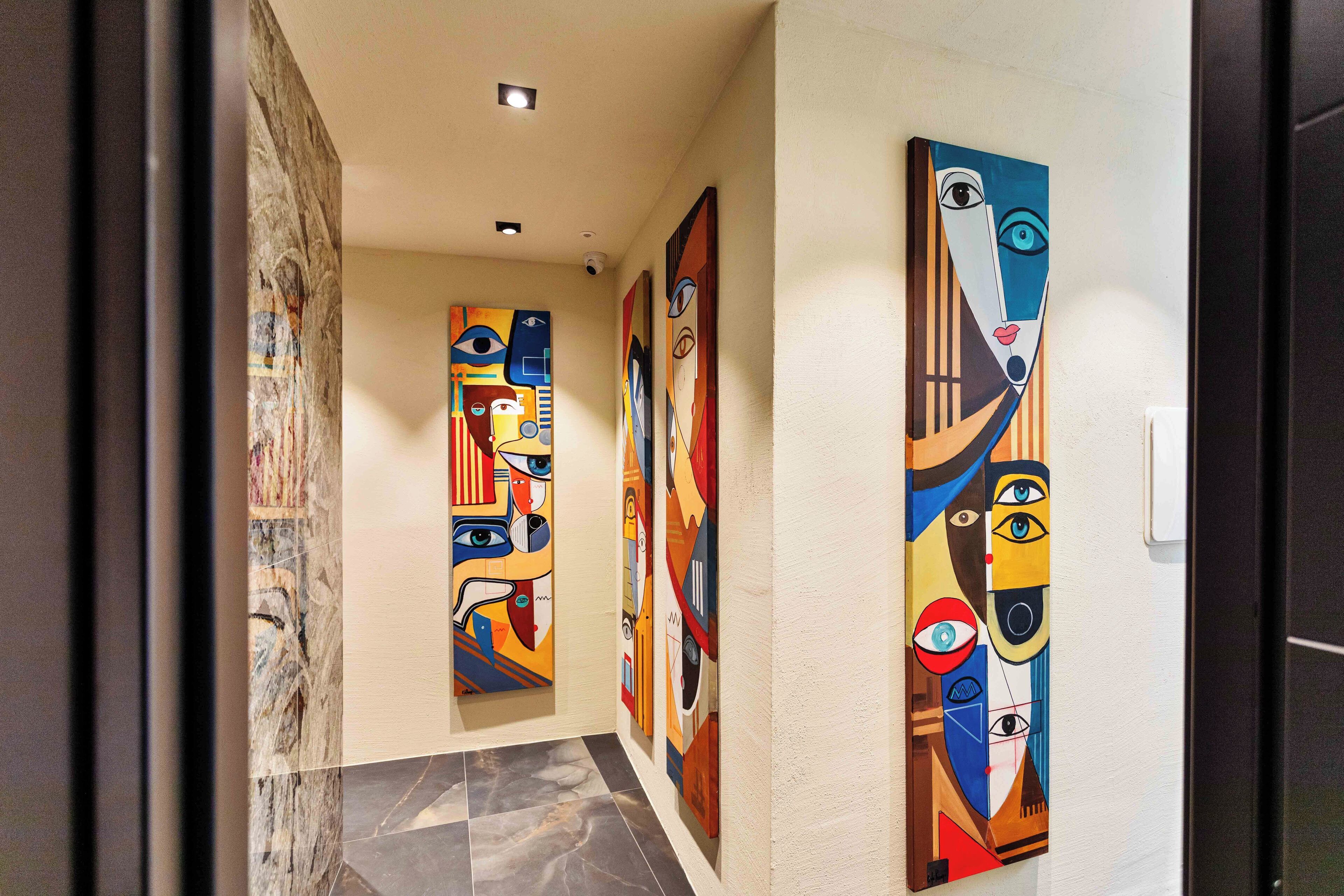 Een gang met abstracte kunst aan de muren en een marmeren vloer.