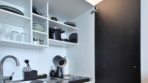 A kitchen with white shelves, a black door, and a sink with a faucet. - RtR Herne (Herne)