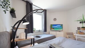 A modern hotel room with two beds, a desk, a TV, and a window with curtains. - RtR Herne (Herne)