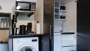 A compact kitchen with a washing machine, a coffee maker, a microwave, and a refrigerator. - RtR Herne (Herne)