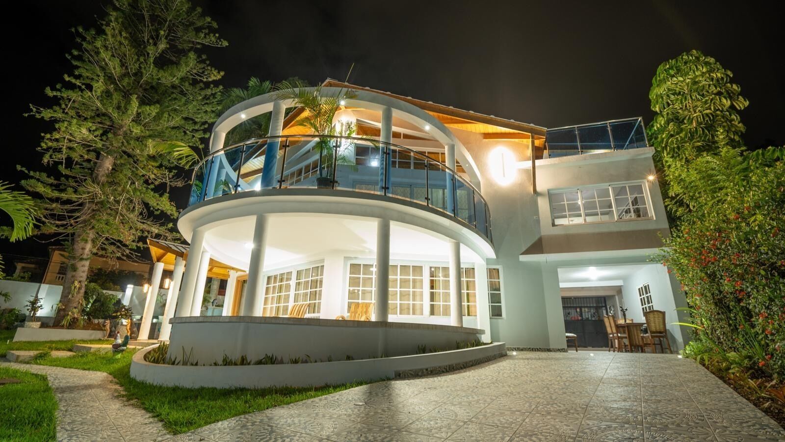 Une maison moderne à plusieurs étages, dotée d’une cour intérieure circulaire, de grandes fenêtres et d’un balcon.