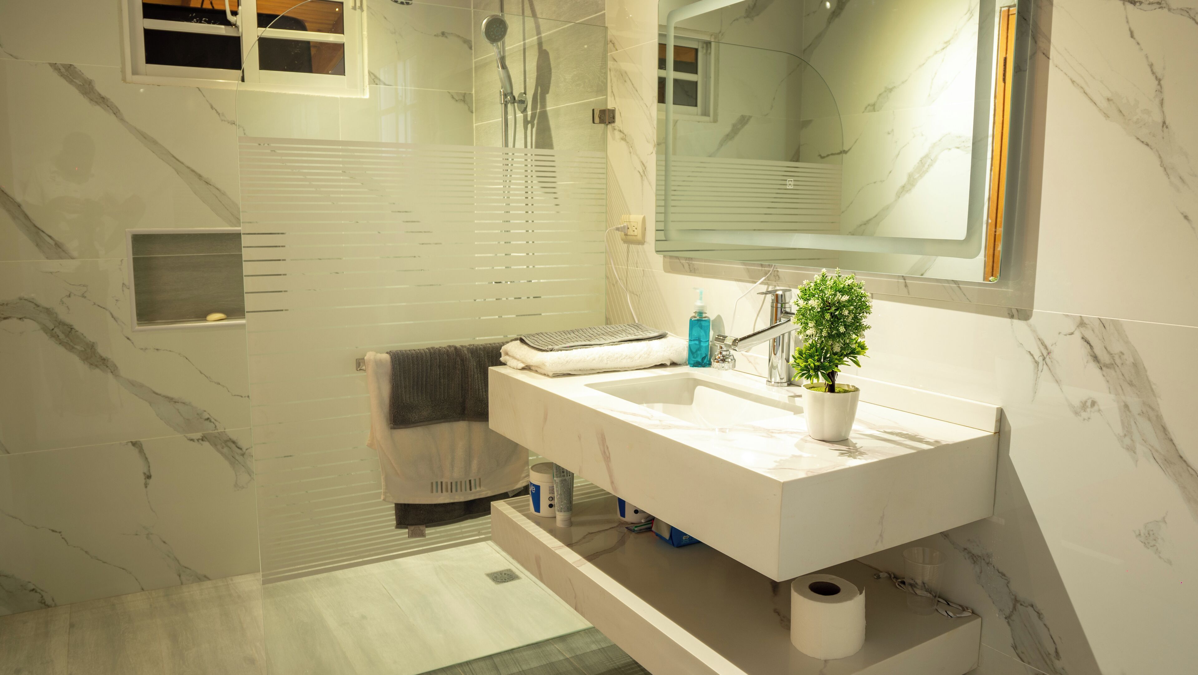 Une salle de bain moderne avec un grand miroir, un lavabo et une douche.