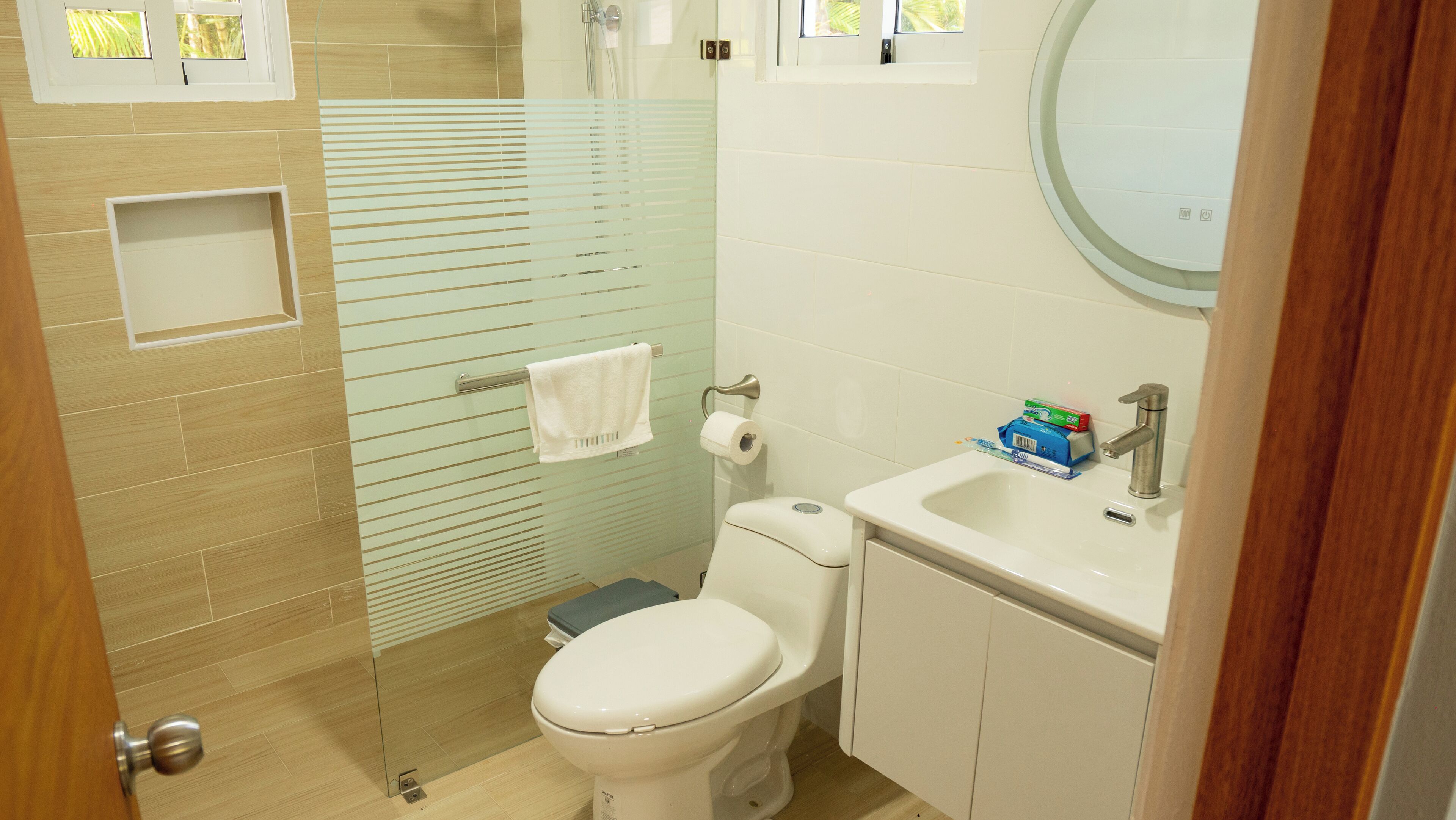 Un baño con inodoro, lavamanos y cabina de ducha de vidrio.