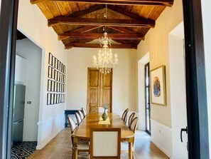Un comedor con una mesa de madera, sillas, una lámpara de araña y cuadros en las paredes.