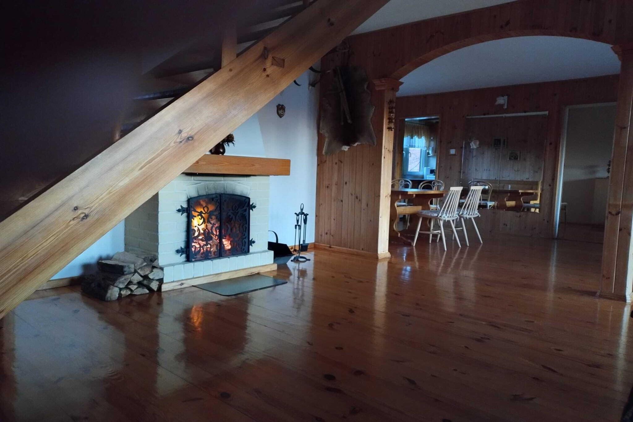 Une pièce spacieuse avec un plancher en bois, une cheminée et un coin repas équipé de chaises.