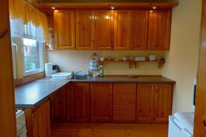 A kitchen with wooden cabinets, a sink, and a window with curtains.