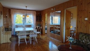 Puisesti sisustettu tila, jossa on ruokapöytä, tuoleja, sohva ja pyöreä sohvapöytä.