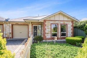A residential house with a garage, a front door, and a well-maintained lawn. - Victor Central Cottage Perfect Location (Victor Harbor)