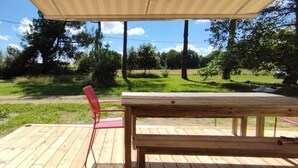 A wooden deck with a picnic table and a red chair, overlooking a grassy area with trees and a clear sky. - WEST COAST house between ocean, Bassin d'Arcachon, Dune du Pyla, Bordeaux (Le Porge)