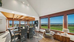 Ein geräumiges Wohnzimmer mit großem Esstisch, bequemen Sitzgelegenheiten und Meerblick.