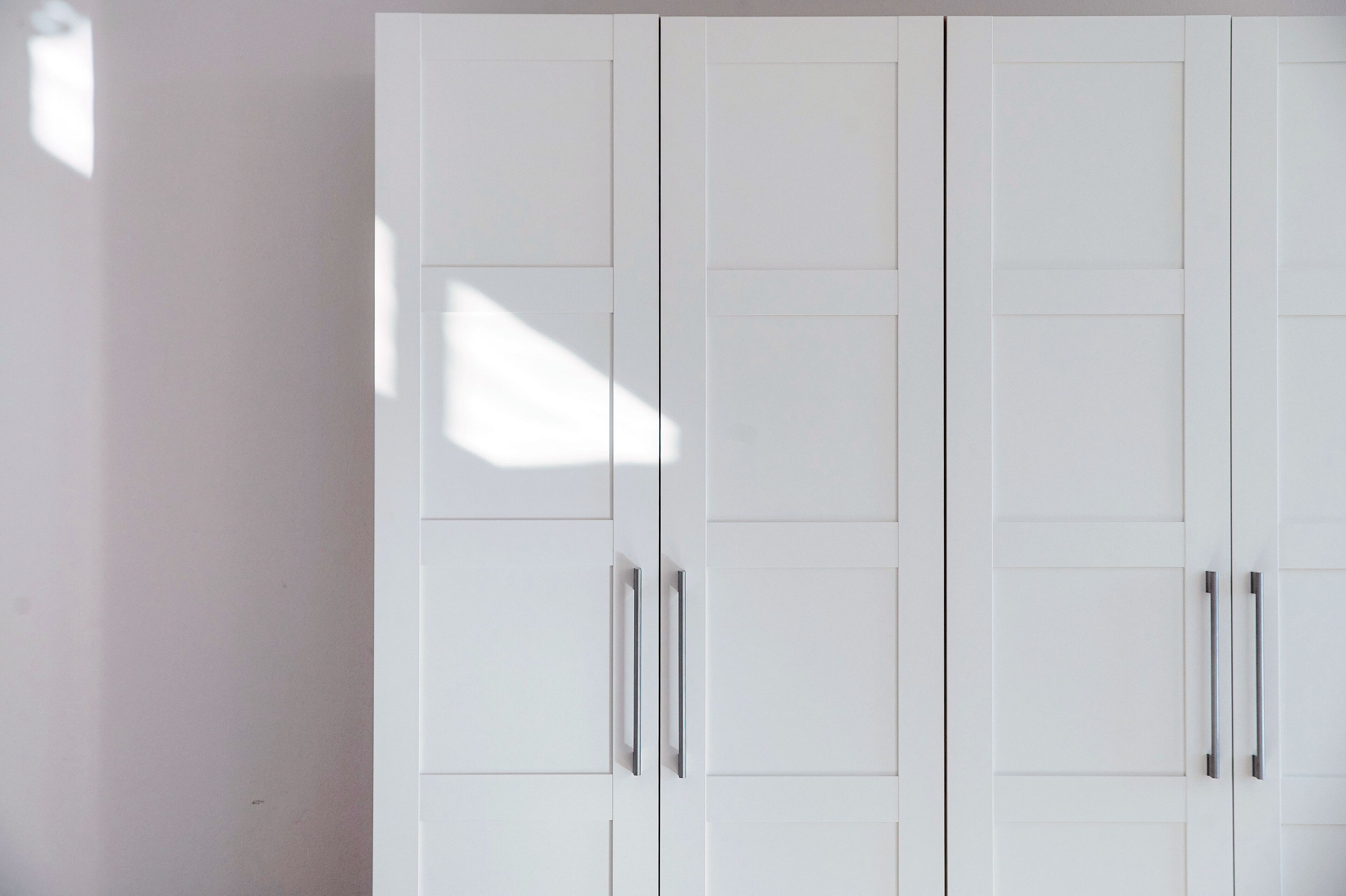 A white wardrobe with two doors and two handles.