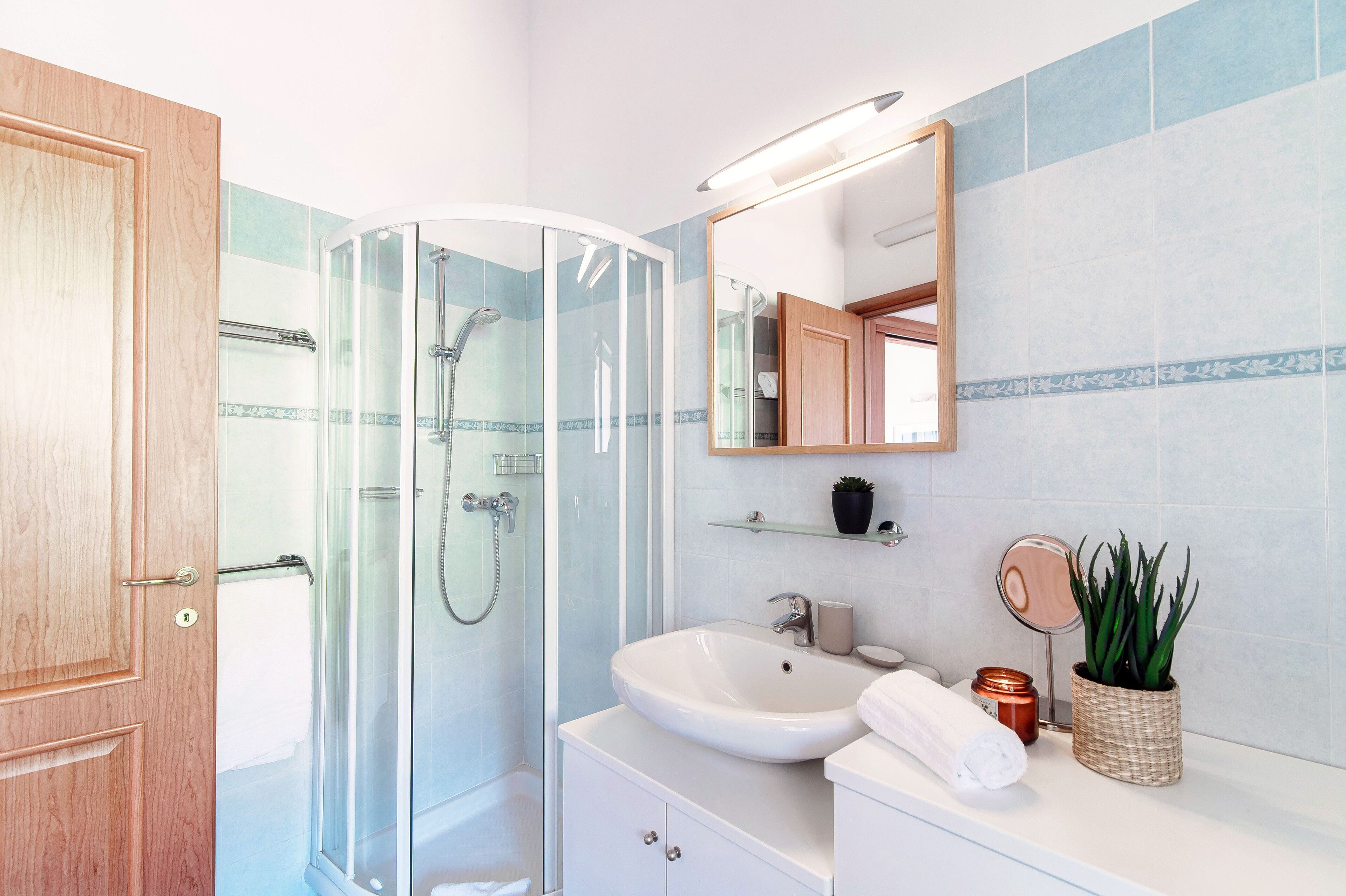 Un baño moderno con cabina de ducha de vidrio, un lavabo blanco y un espejo encima.
