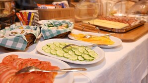 Un tavolo per buffet con diversi cibi, tra cui pomodori a fette, cetrioli e formaggio.